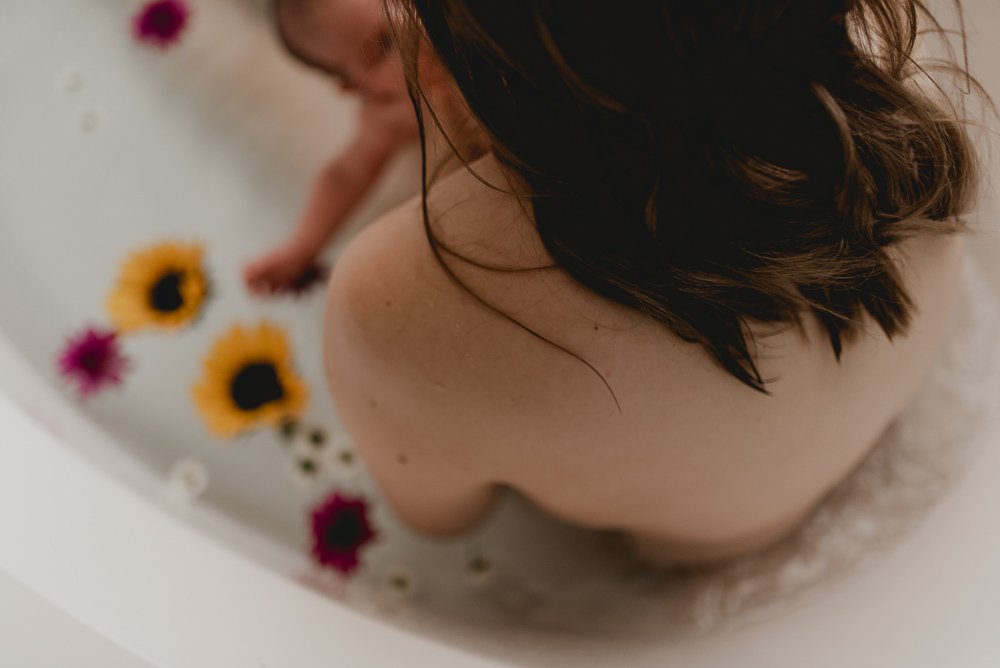 Postpartum mom taking a floral bath with her baby