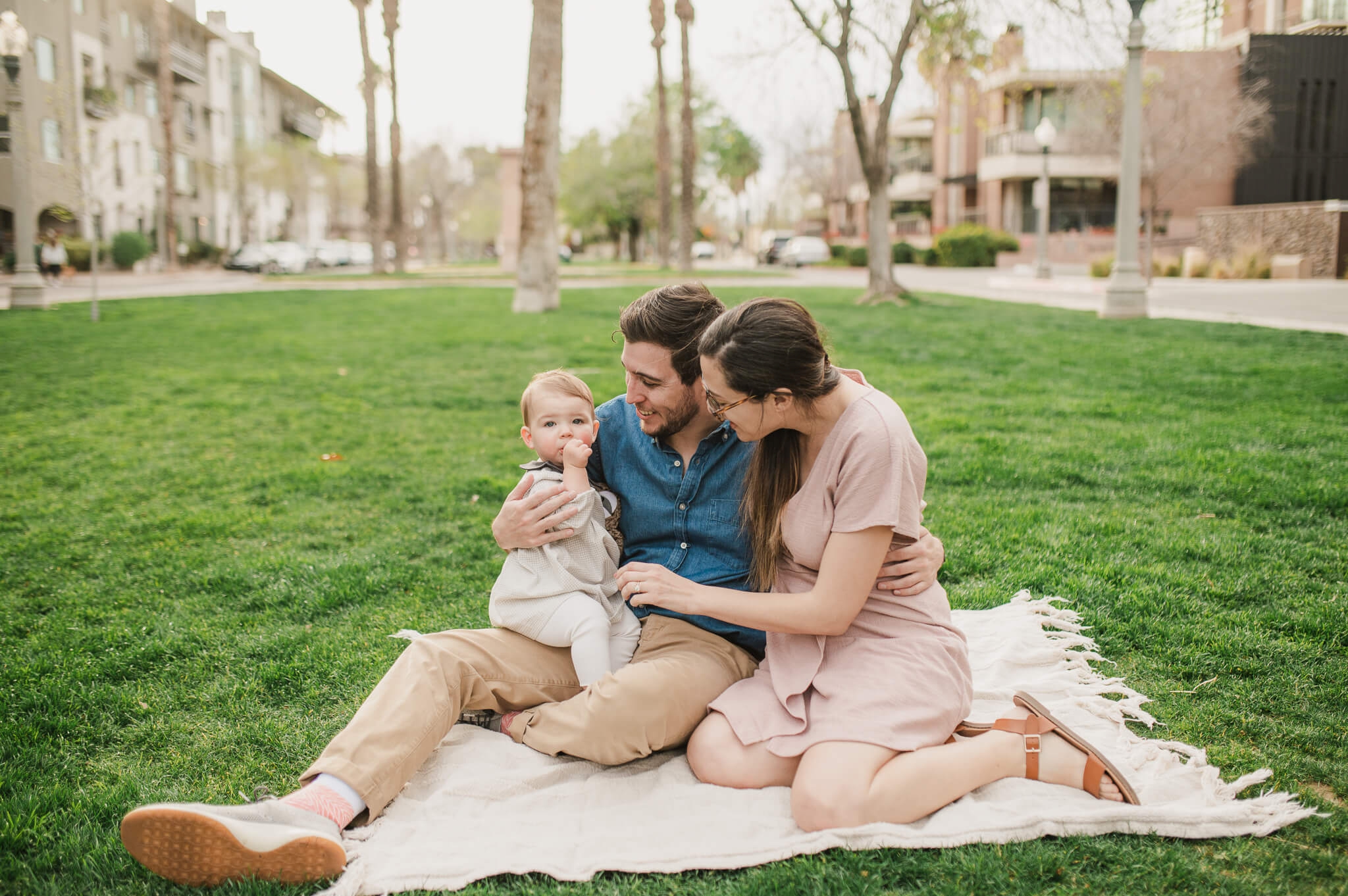 family of three sitting on a blanket at a green park in downtown Phoenix