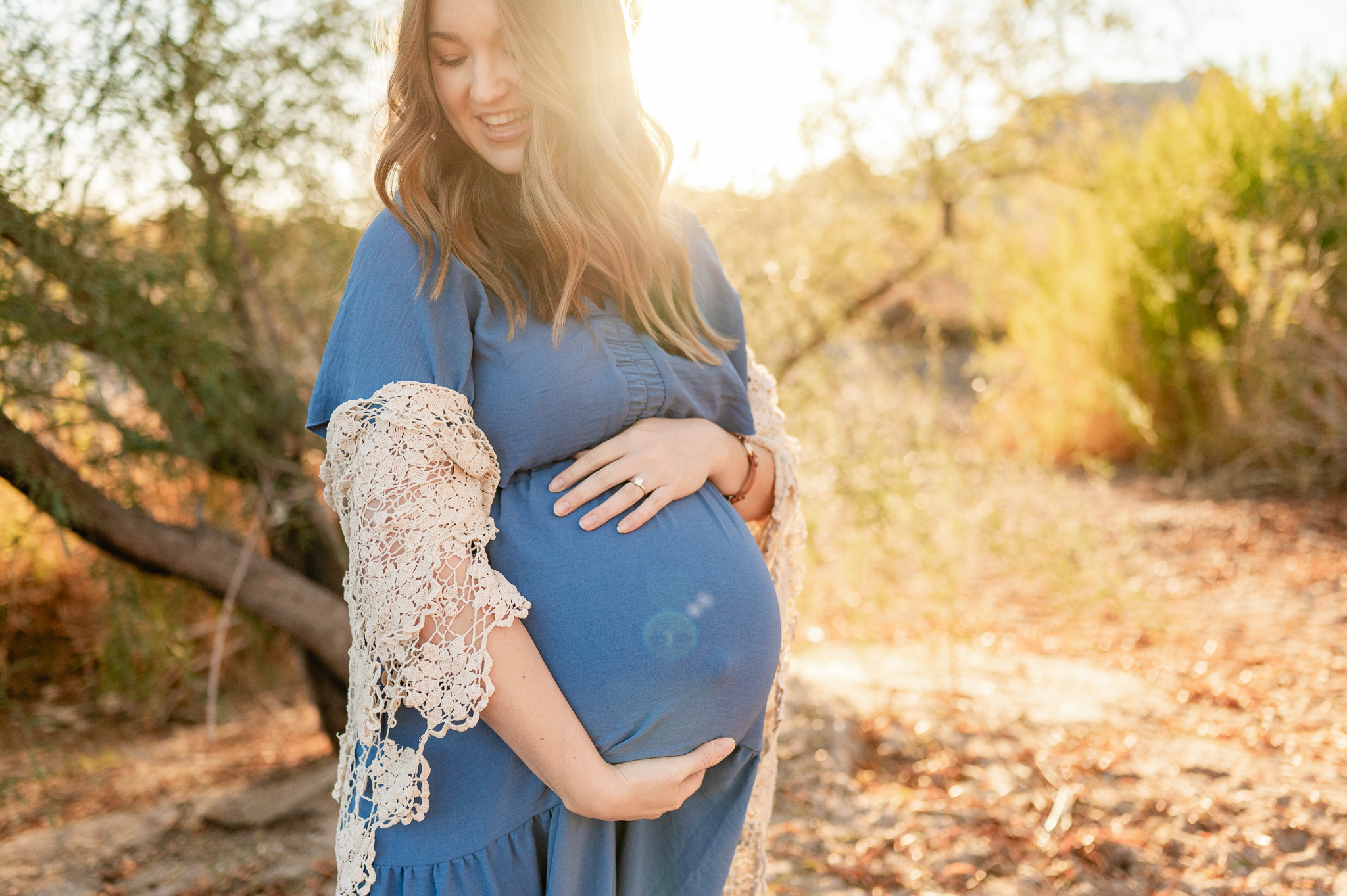 pregnant mama in a blue dress and cream shawl standing among the trees at Phon D sutton one of the best places for family photos in Phoenix 