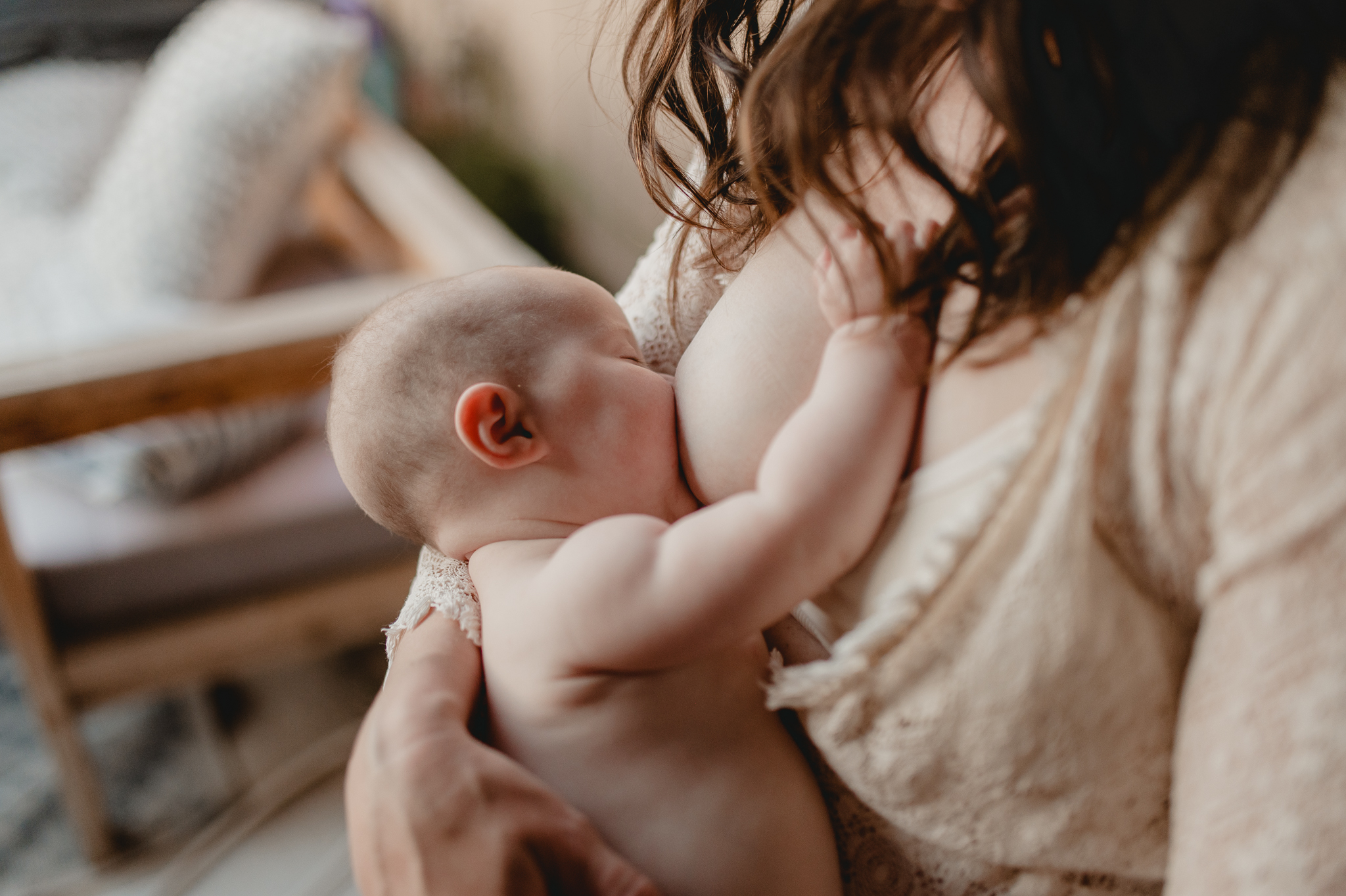 mom in a lace robe holds her naked infant 