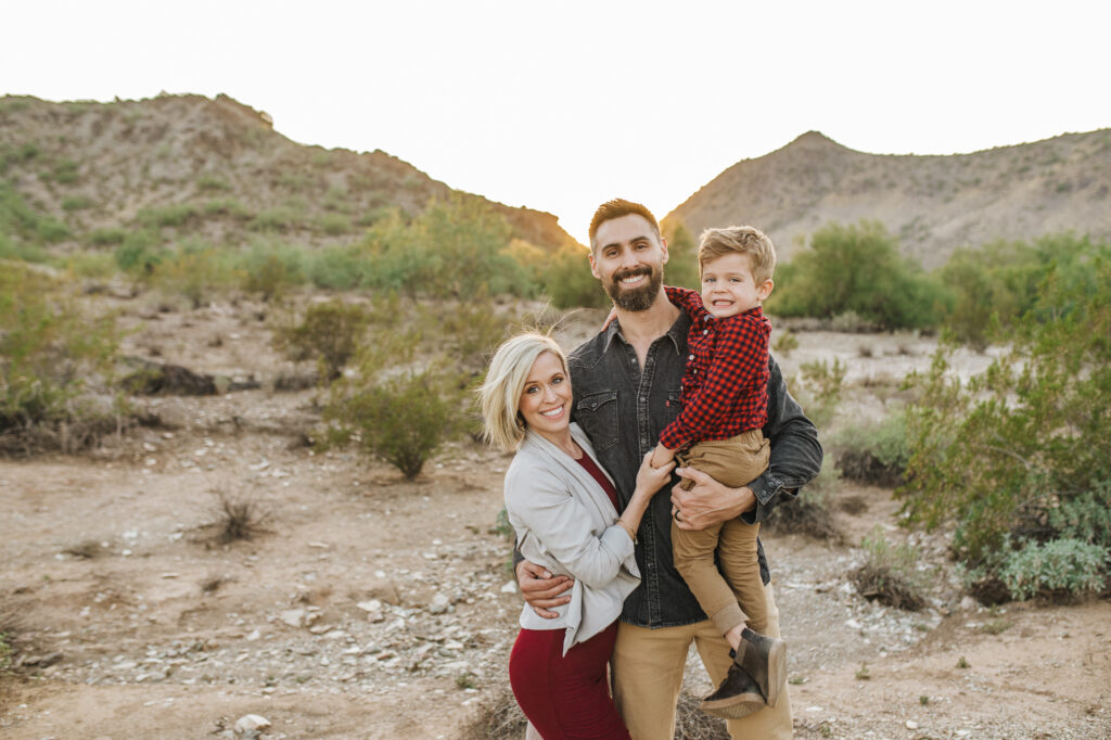 mom, dad and son in coordinating red and grey outfits posing in the desert while enjoying their stay at one of the best family-friendly resorts in Scottsdale