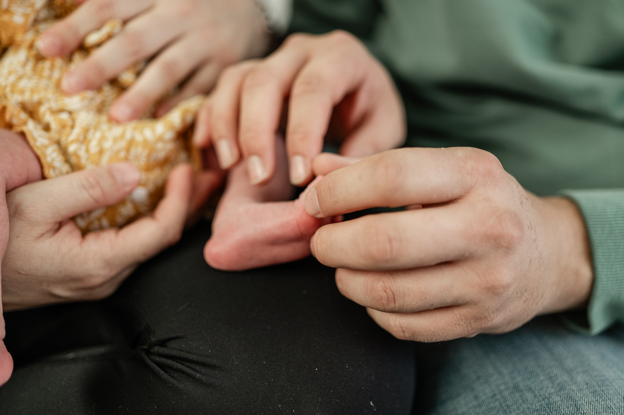 Details of a father holding the toes of his newborn daughter