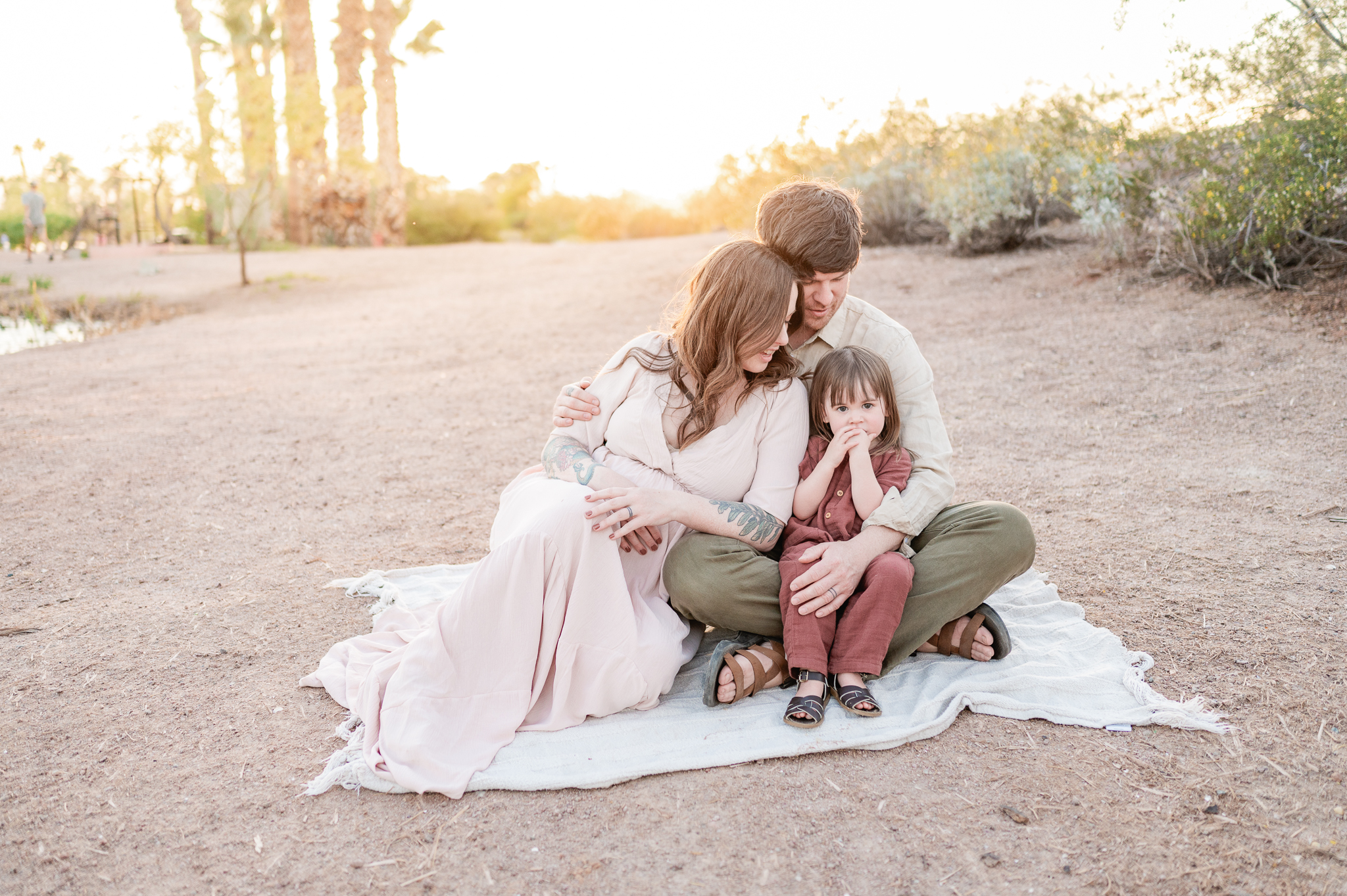 pregnant mom snuggling with her husband and daughter in Papago Park after seeing her 3D ultrasound at Miracle View Ultrasound