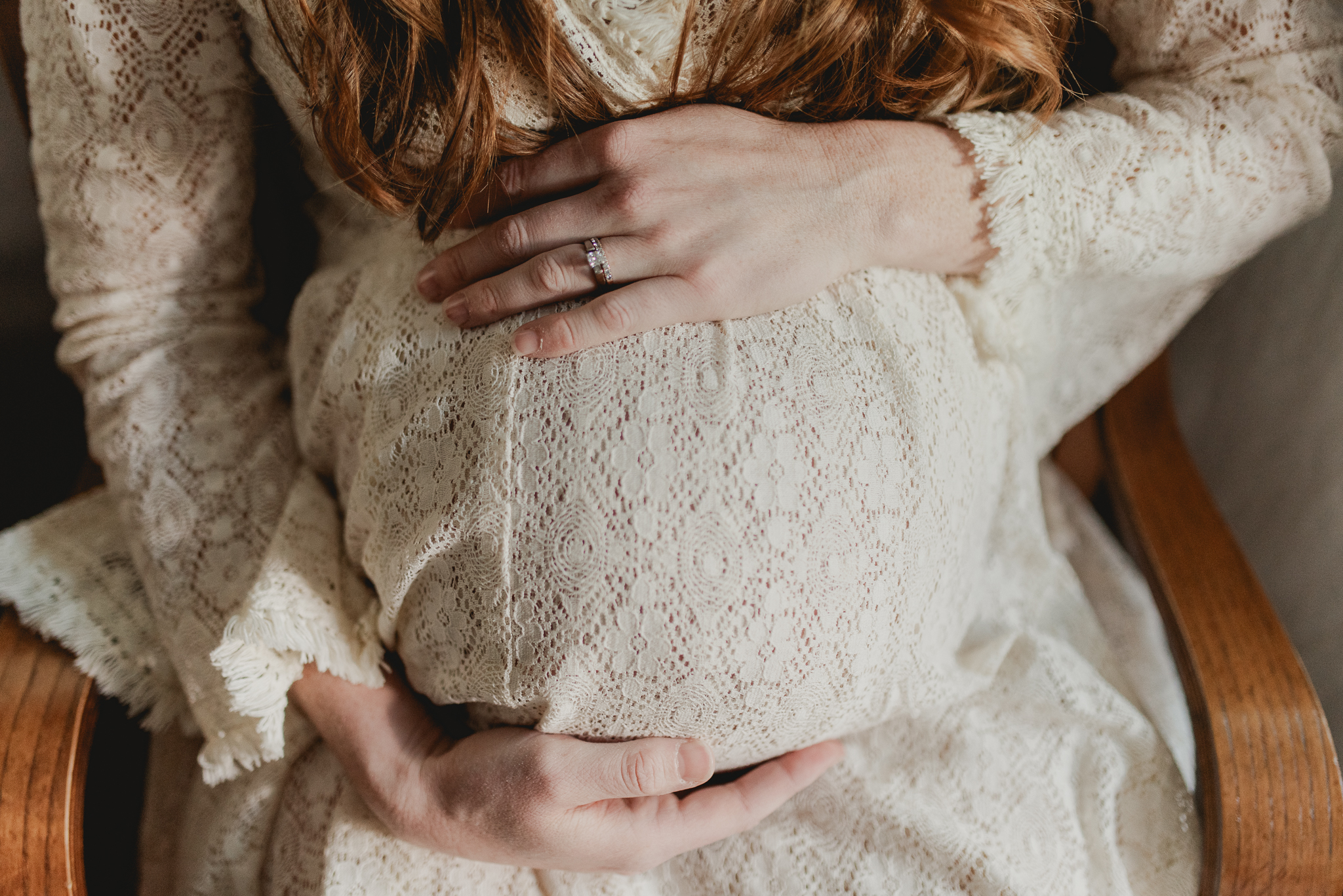 Phoenix mom holding her pregnant belly while she sits on the rocking chair in her home before her birth with midwife Crystal Pena