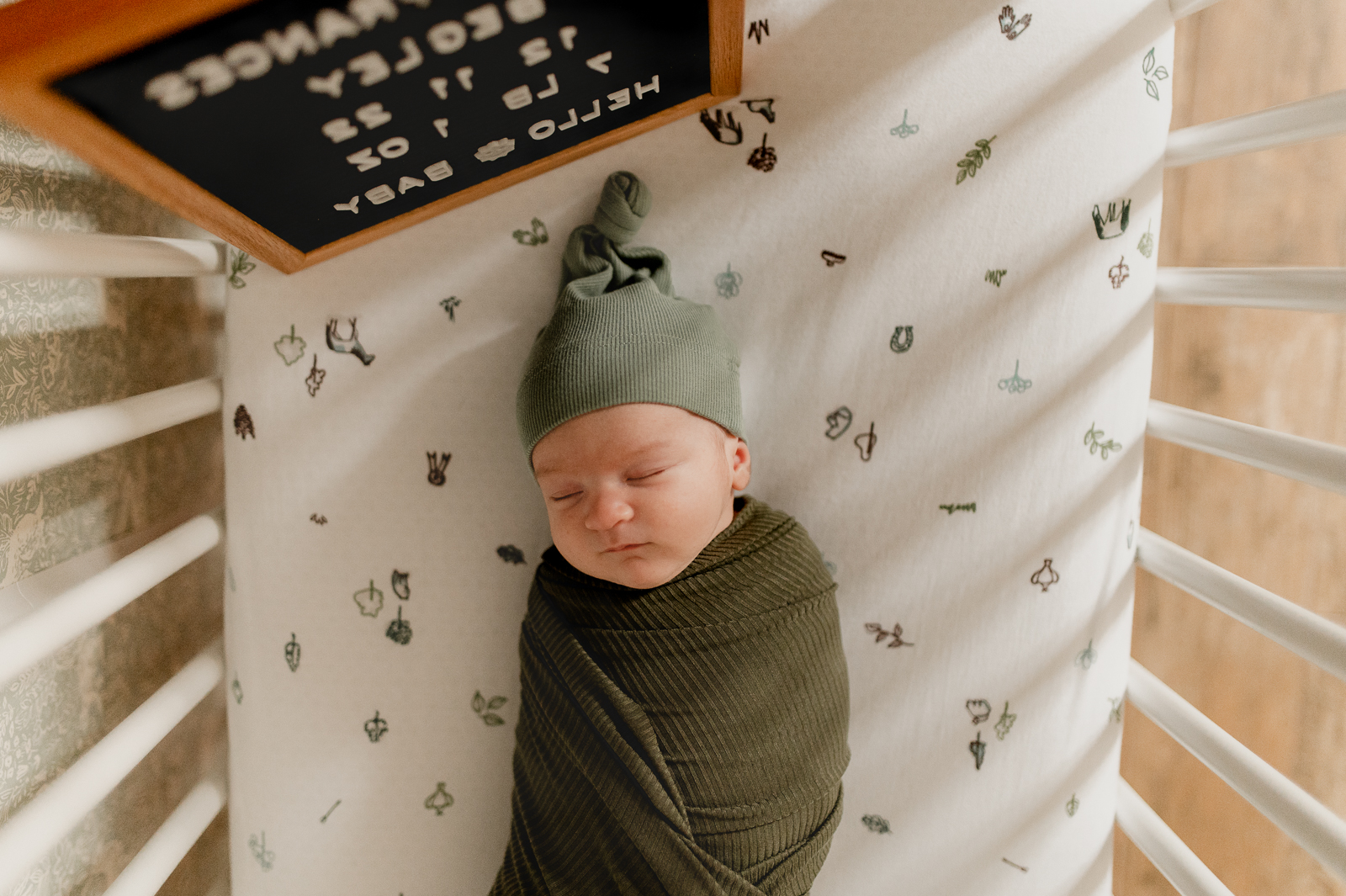 swaddled newborn laying in her crib during a newborn photo session